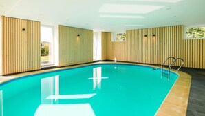 An indoor swimming pool with wooden panel walls, a tiled floor, and a metal ladder. - Luxurious Villa With Pool and Sauna, and Very Suitable for Culinary Workshops (Waimes)