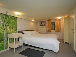 A bedroom with a bed, bedside table, and a wall with a nature-themed wallpaper. - Rendeux Villa With Garden (Rendeux)