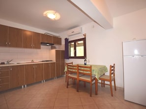 A compact kitchen with wooden cabinets, a gas stove, a sink, and a dining table with chairs.