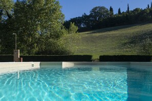 A swimming pool with clear water, surrounded by a grassy area and trees.
