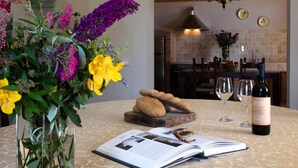 A dining table with a book, glasses, and a bottle of wine, surrounded by a variety of flowers. - Villa in Tuscany Near Medieval Ghizzano (Peccioli)