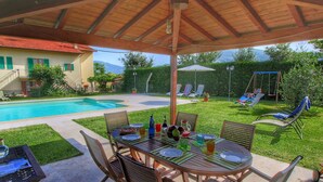 Ein überdachter Patio mit Pool, Esstisch und Stühlen.