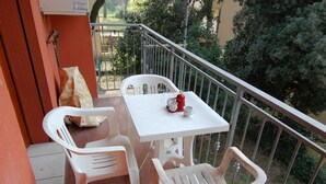 A balcony with a white table and two white plastic chairs, a red fire hydrant, and a bag of snacks. - Sun Drenched Seaside Holiday Home near Venice (Rosolina)