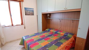 A bedroom with a bed, a window with curtains, a poster on the wall, and a wooden wardrobe. - Sun Drenched Seaside Holiday Home near Venice (Rosolina)