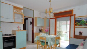 A compact kitchen with a dining area, a sofa, and a painting on the wall. - Sun Drenched Seaside Holiday Home near Venice (Rosolina)