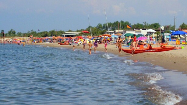 A beach with numerous colorful umbrellas and a boat on the shore.