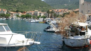 A marina with boats docked, surrounded by traditional buildings and a mountainous backdrop. - Coastal Apartment in Vis Near sea (Vis)