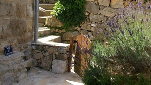 A stone staircase leading up to a door, surrounded by greenery and lavender plants. - Coastal Apartment in Vis Near sea (Vis)