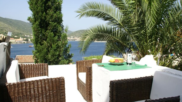 Wicker furniture, a table with fruits and a glass, and a view of the sea and hills. - Coastal Apartment in Vis Near sea (Vis)