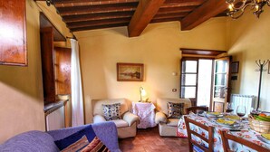 A cozy living room with a sofa, two armchairs, a dining table set for two, and a chandelier. - Escape to Vineyards, Elba (Radda in Chianti)