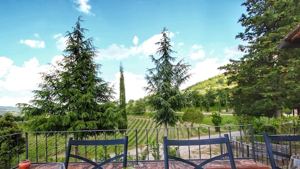 An outdoor dining area with a table set for two, overlooking a vineyard and a scenic landscape. - Escape to Vineyards, Elba (Radda in Chianti)
