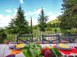 An outdoor dining area with a table set for two, overlooking a vineyard and a scenic landscape. - Escape to Vineyards, Elba (Radda in Chianti)
