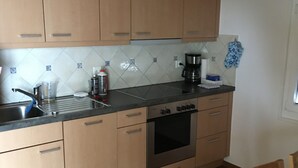 A kitchen with wooden cabinets, a stainless steel oven, and a coffee maker. - Spacious Apartment in Riederalp near Ski Trail (Riederalp)