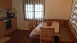 A compact kitchen with wooden cabinets, a stove, and a window with striped curtains. - Spacious Apartment in Riederalp near Ski Trail (Riederalp)