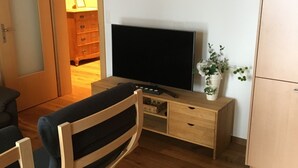 A room with a wooden desk, a television, a chair, a dresser, and a plant. - Spacious Apartment in Riederalp near Ski Trail (Riederalp)