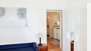 A bedroom with a bed, a small table with a lamp, and a door leading to a kitchen area. - Delightfully Decorated Apartment with Sea View near Beach (Brela)