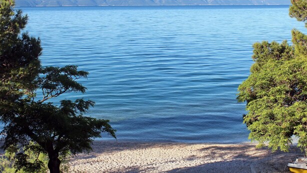 A lake with a clear view of distant mountains, surrounded by trees. - Delightfully Decorated Apartment with Sea View near Beach (Brela)