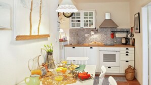 A kitchen with white cabinets, a stove, and a hanging light fixture. - Delightfully Decorated Apartment with Sea View near Beach (Brela)