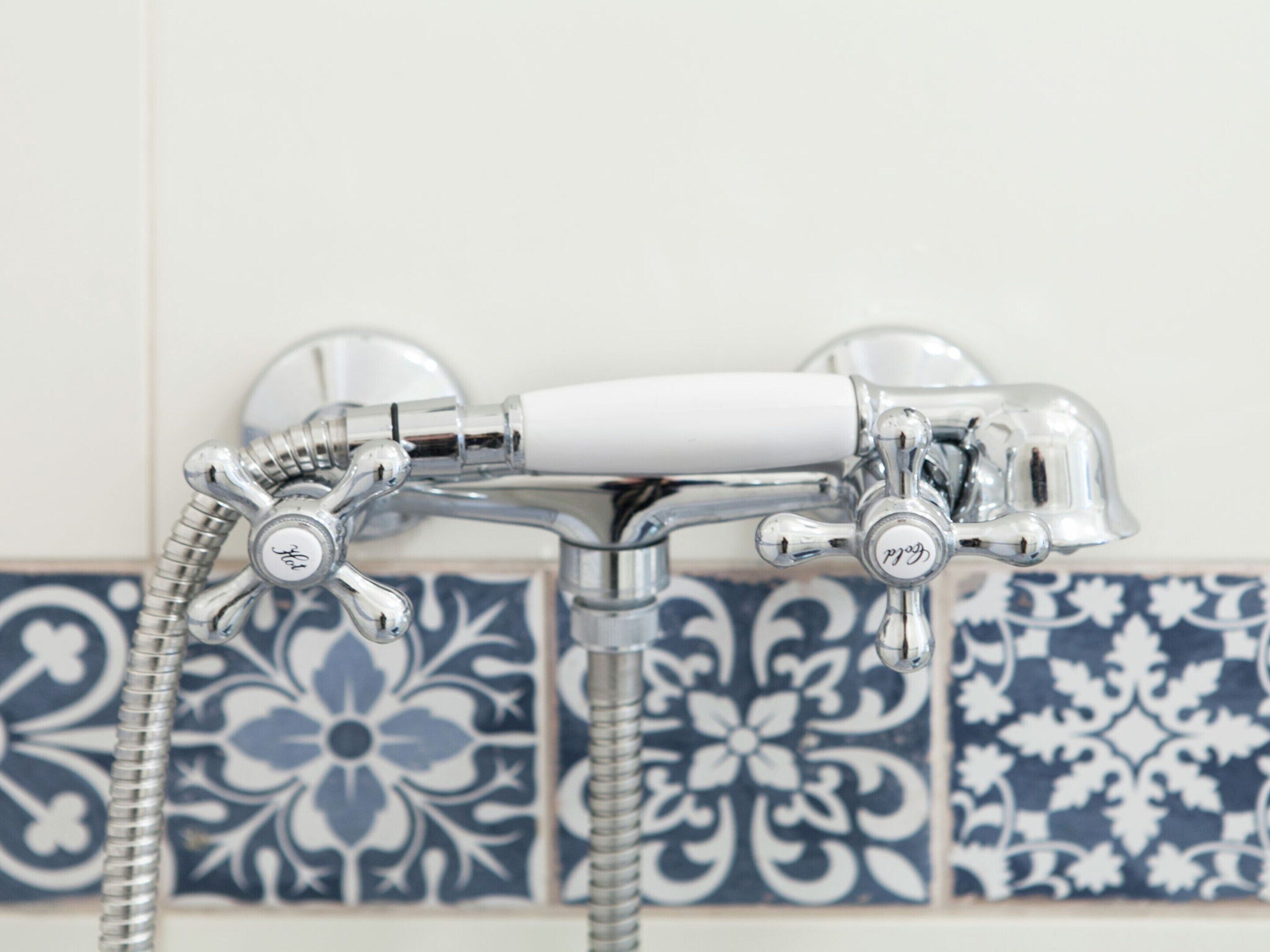A bathroom with a classic chrome showerhead and a white handle.