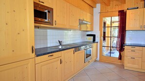 Una cocina con armarios de madera, un lavamanos de acero inoxidable y un salpicadero de azulejos.