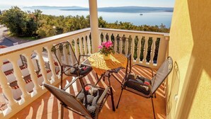 A balcony with a table and four chairs, overlooking a body of water and greenery. - Country House in Croatia With Pool (Crikvenica)