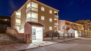 A multi-story residential building with balconies, a gated entrance, and a parking area. - Country House in Croatia With Pool (Crikvenica)