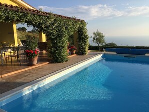 A swimming pool with a clear blue water, surrounded by a patio area with chairs and potted plants. - Bungalow in Maratea With Pool Near Beach (Maratea)