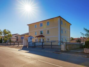 A multi-story hotel with a yellow facade, a gated entrance, and a clear sky.