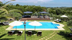 Un espace piscine aménagé avec des chaises longues, des parasols et un barbecue.
