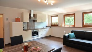 Une cuisine moderne avec des armoires blanches, un four encastré et un coin repas avec une table dressée pour deux personnes.