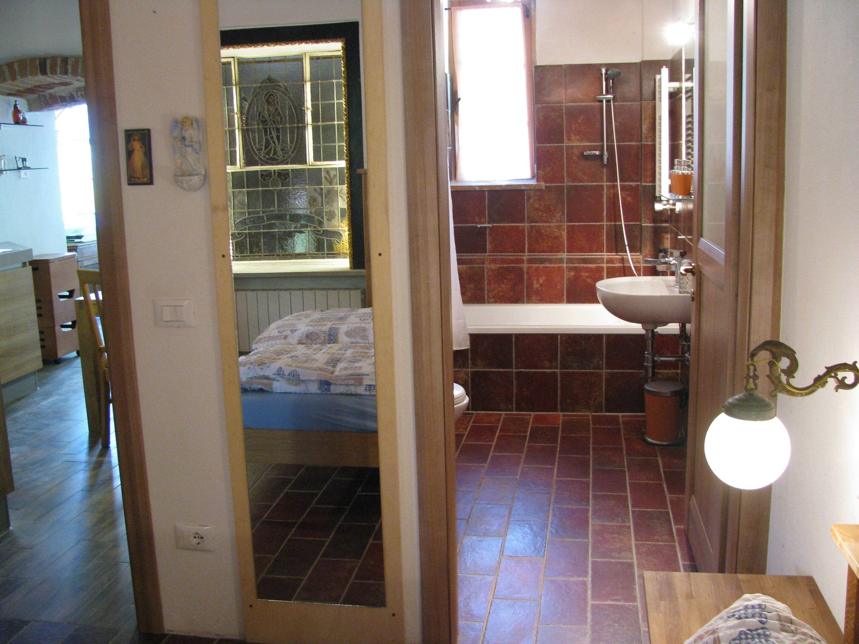 Une salle de bain équipée d’une douche, d’un lavabo et d’une fenêtre agrémentée d’un panneau de verre décoratif.