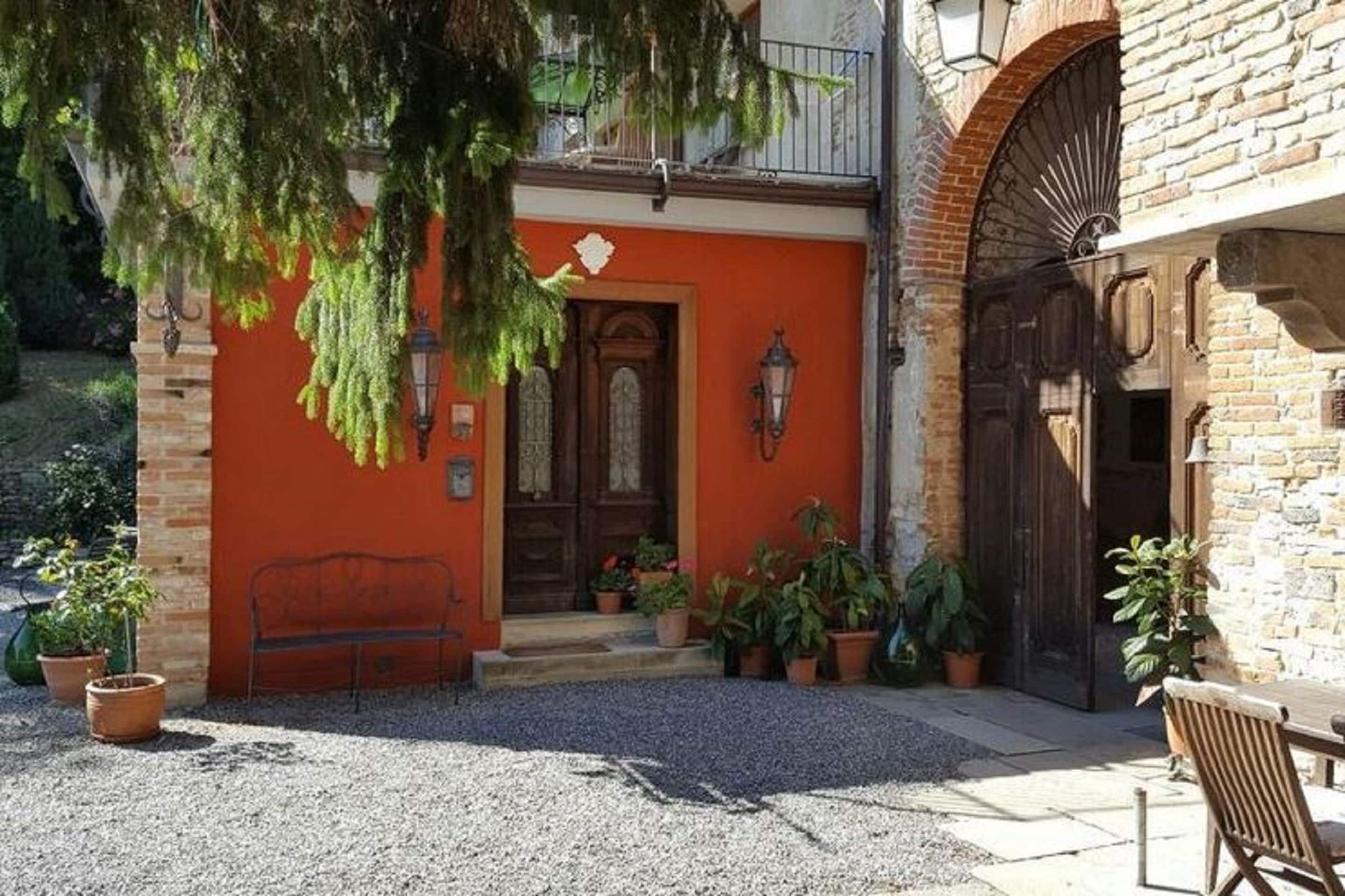 A building with a red facade, a wooden door, and a brick entrance.