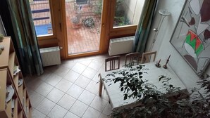 A room with a tiled floor, a table with chairs, a radiator, and a window with curtains. - Idyllically located in the center of Coswig (Coswig)