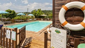Uma área de piscina com deck de madeira, espreguiçadeiras e guarda-sóis.