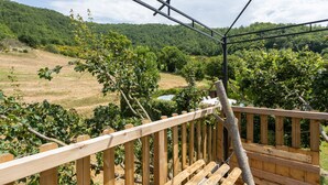 Um deck de madeira com vista para um vinhedo e um rio.