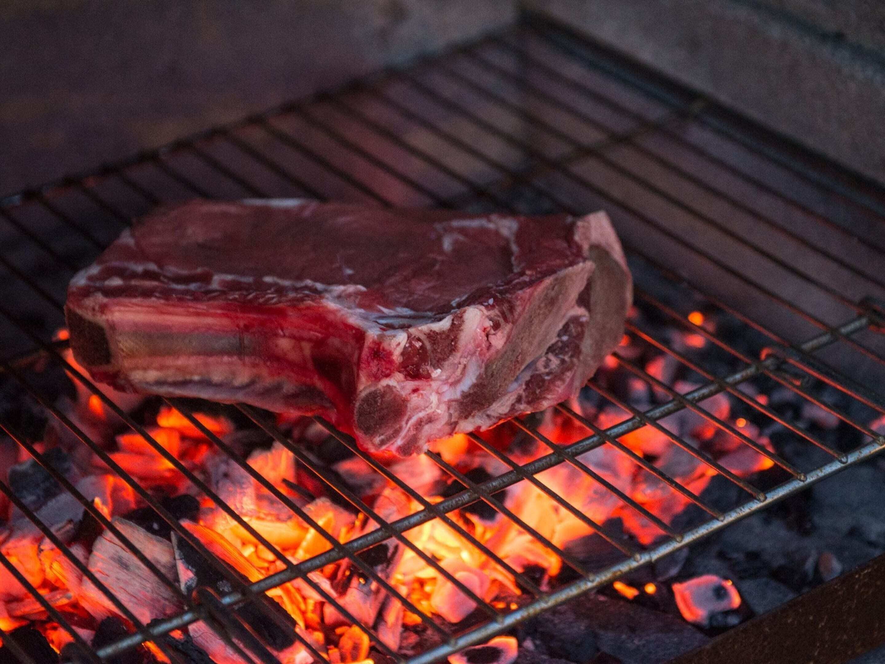 Ein großes Stück Fleisch wird über offenem Feuer gegrillt.