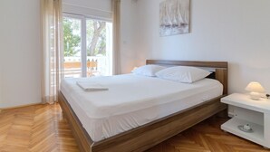 A neatly made bed with white linens, a wooden headboard, and a bedside table with a lamp. - Apartment in Senj With Sea Views & BBQ (Senj)