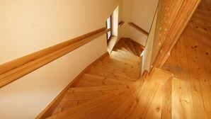 A wooden staircase with a handrail, leading to a landing with a small window.