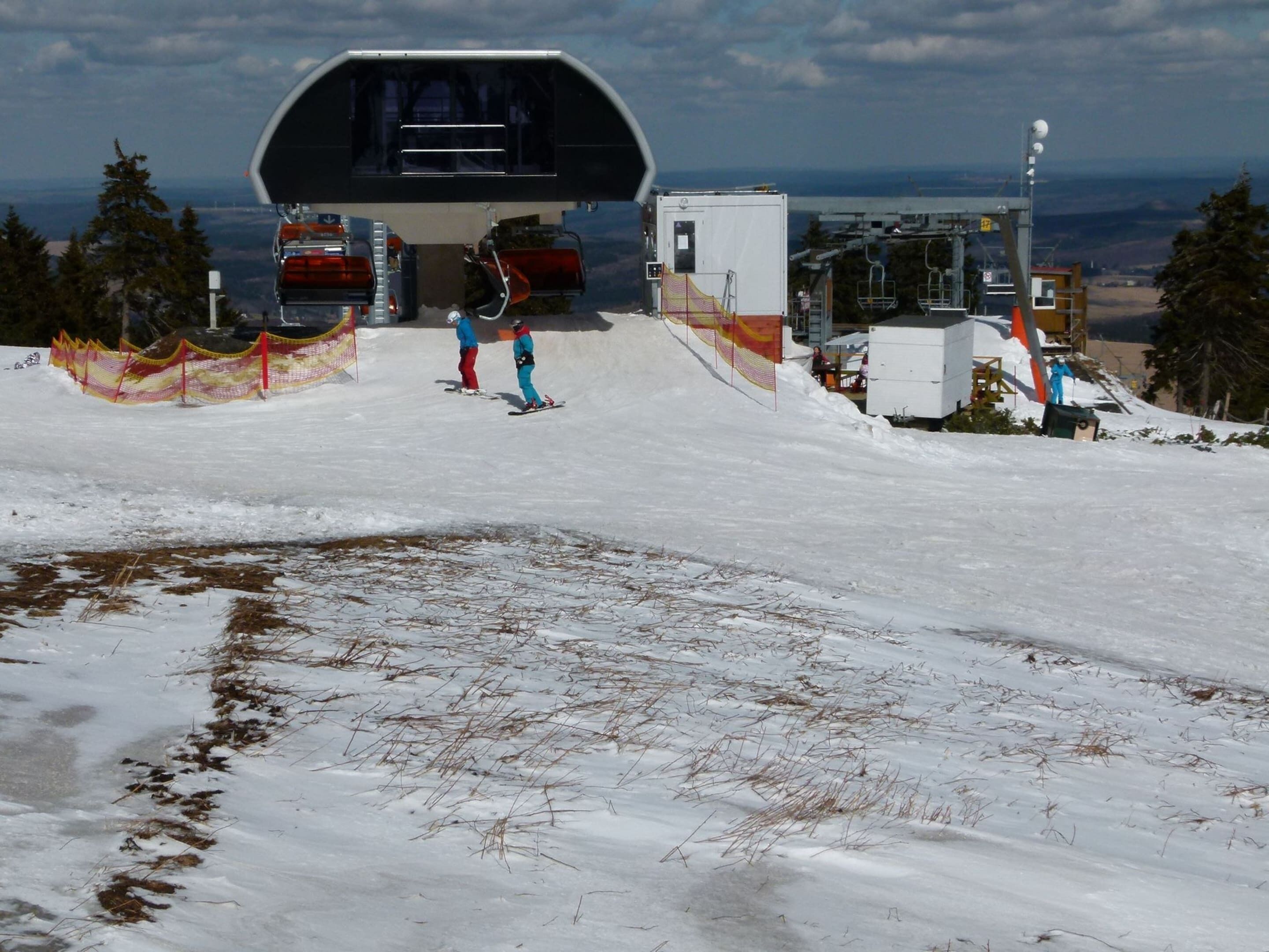 A ski lift station with a covered waiting area and a view of the snowy landscape.