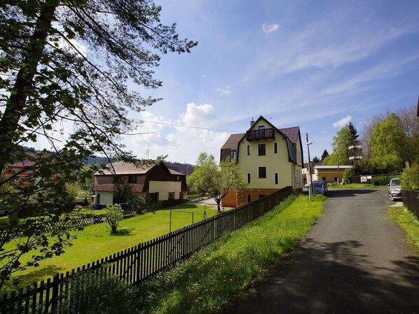 Une maison  à deux étages avec un toit en pente, un balcon et une cour clôturée.