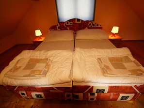A double bed with a quilt, two bedside lamps, and a window with curtains. - Holiday Home in Pernink in a Beautiful Mountainous (Pernink)