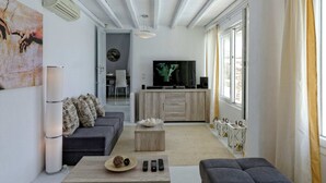 A modern living room with a sofa, coffee table, and a TV in the background. - Villa in Mykonos With Sea View and Pool (Mykonos)