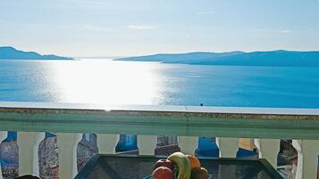 Un balcon offrant une vue sur une mer calme et des montagnes lointaines.