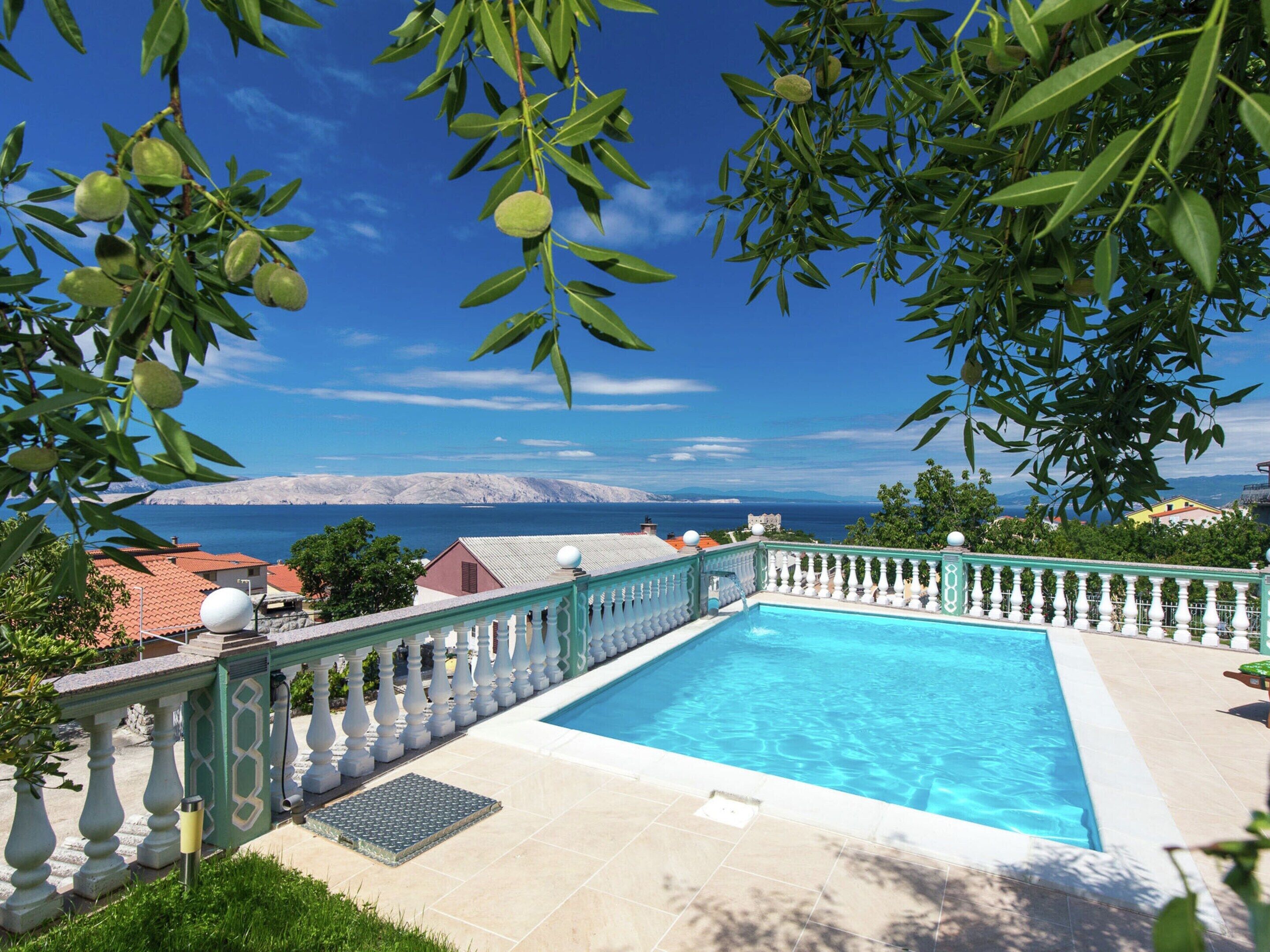 A swimming pool with a view of the sea and mountains in the background.