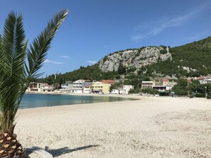 A beach with buildings in the background and a mountain.
