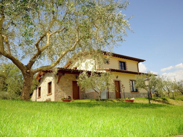 A stone house with a tiled roof, surrounded by a grassy field and olive trees. - Secluded Mansion in Perugia with Hot Tub (Perugia)