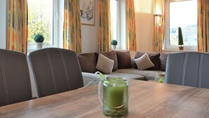 A cozy living room with a sofa, chairs, a table with a green drink, and a city view through large windows. - Modernes Apartment in Willingen mit Balkon (Willingen)