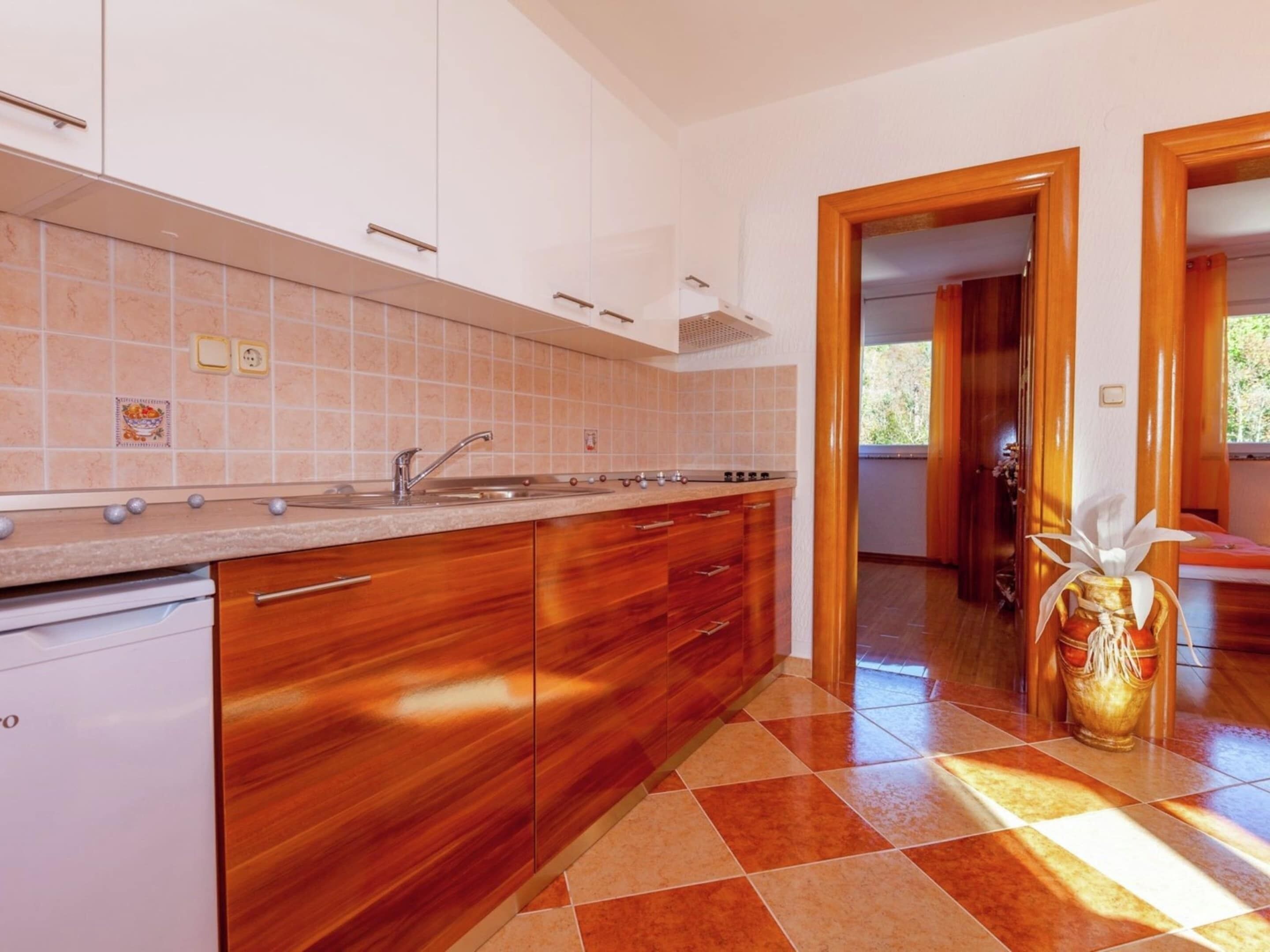 Une cuisine moderne avec des meubles en bois, un évier en acier inoxydable et un dosseret carrelé.