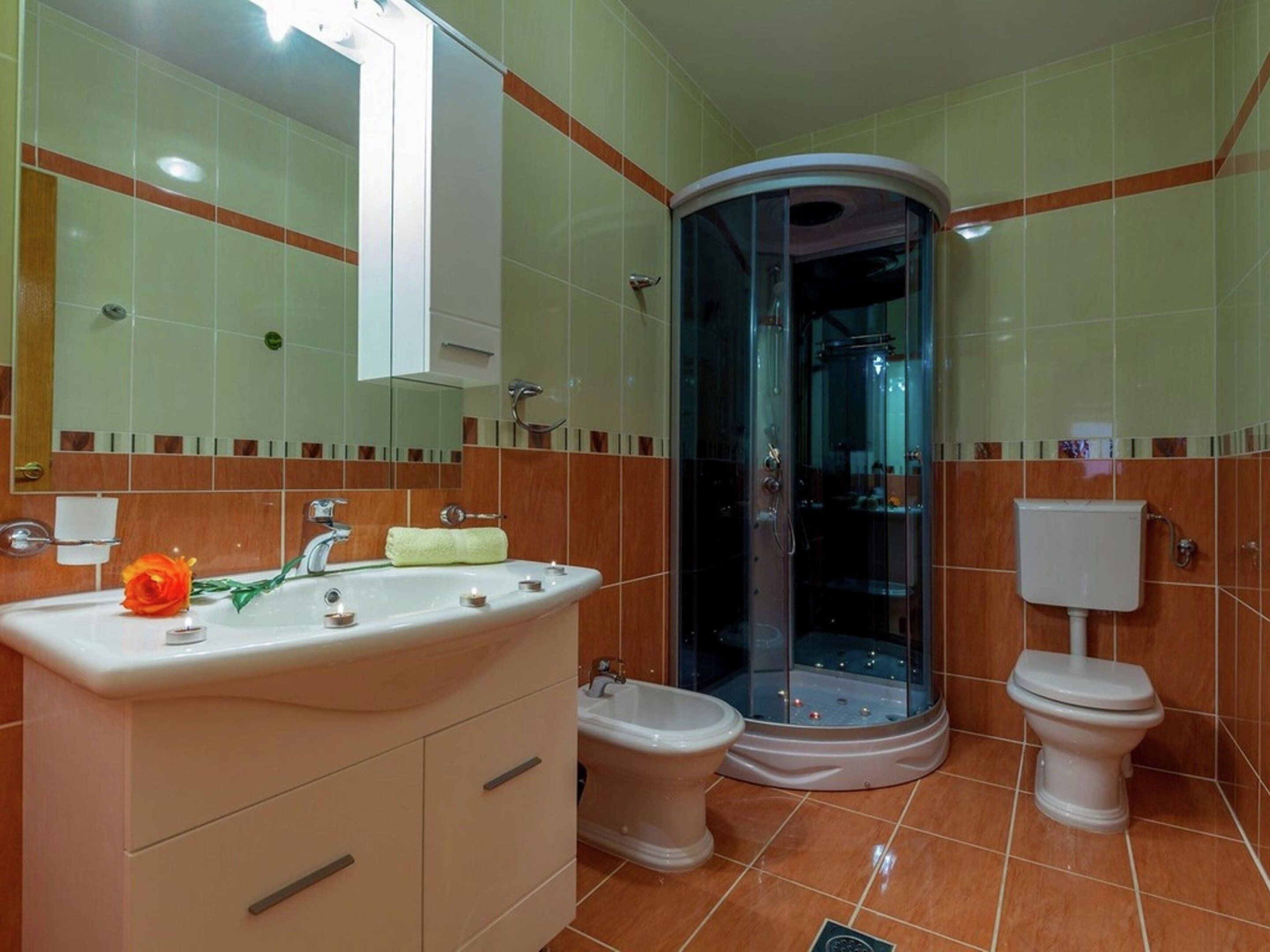 Een badkamer met een wastafel, twee toiletten, een douche en een spiegel.