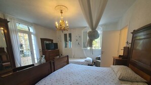 A bedroom with a large bed, a wooden dresser, a television, and a chandelier. - Peaceful Apartment in Modigliana With Swimming Pool (Modigliana)